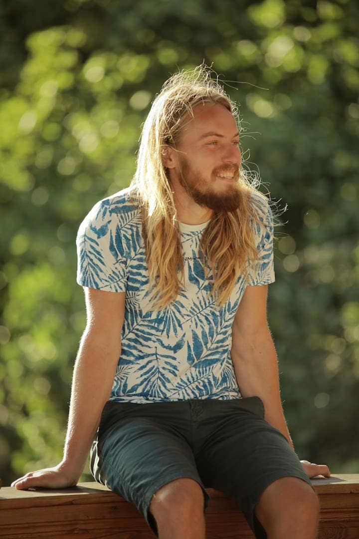 A person sitting on a wooden wall with sunlight shining on their hair from behind.