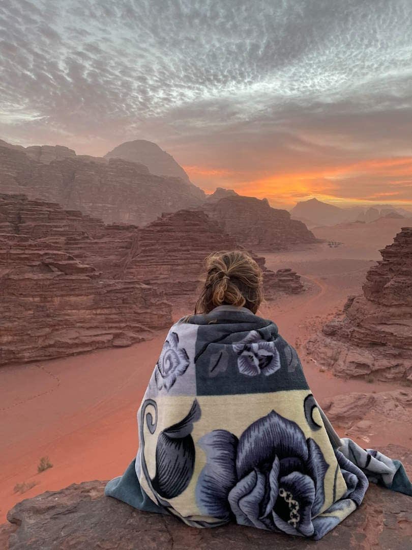 Osoba sedící v poušti Wadi Rum.