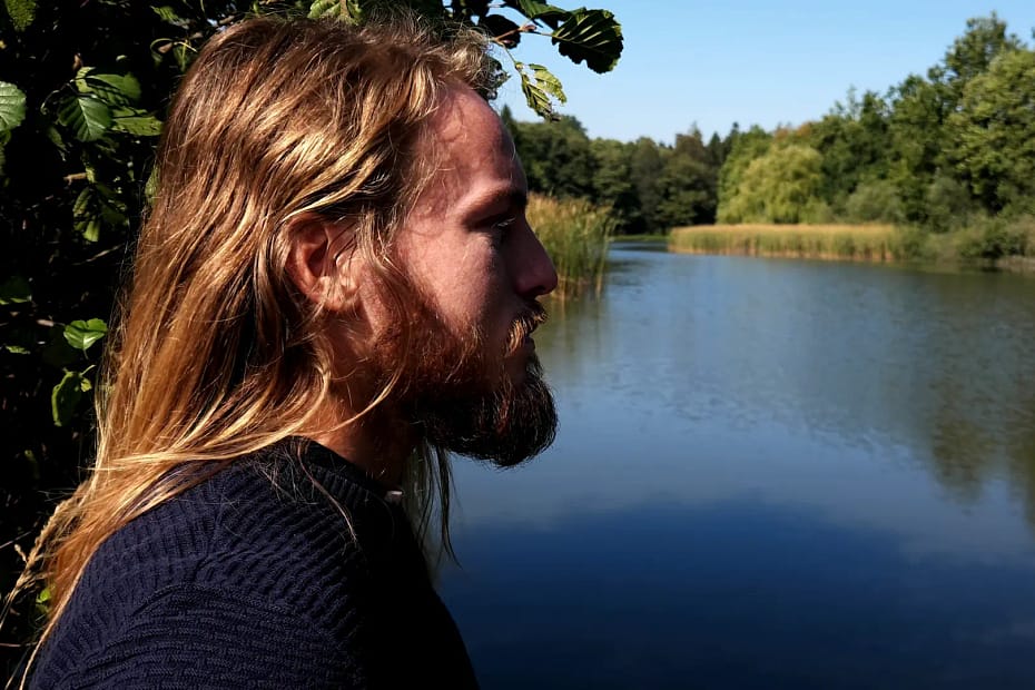 Jaroslav Vašák standing beside a pond, looking thoughtfully at the water, reflecting the journey of overcoming the fear of protein.